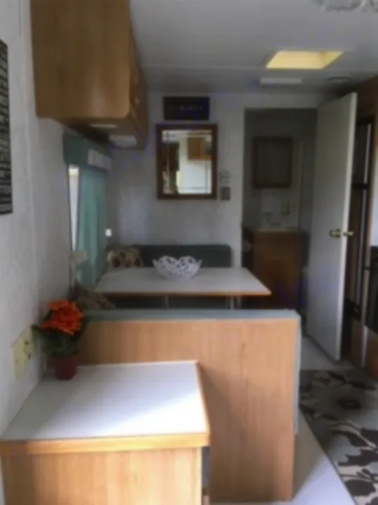 Explore this RV rental's functional interior. It offers a compact living space with a bed, light wood storage, and a mirror.. Electra Electra 1996