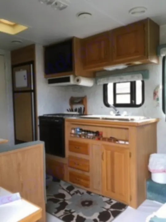 Inside an RV rental: a compact kitchen with wood cabinets, appliances, and a cozy living space, perfect for adventures.. Electra Electra 1996