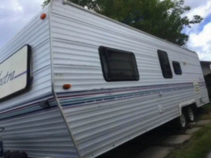 This white travel trailer, ideal for an RV rental, features multiple windows and decorative stripes. Ready for your next adventure!. Electra Electra 1996