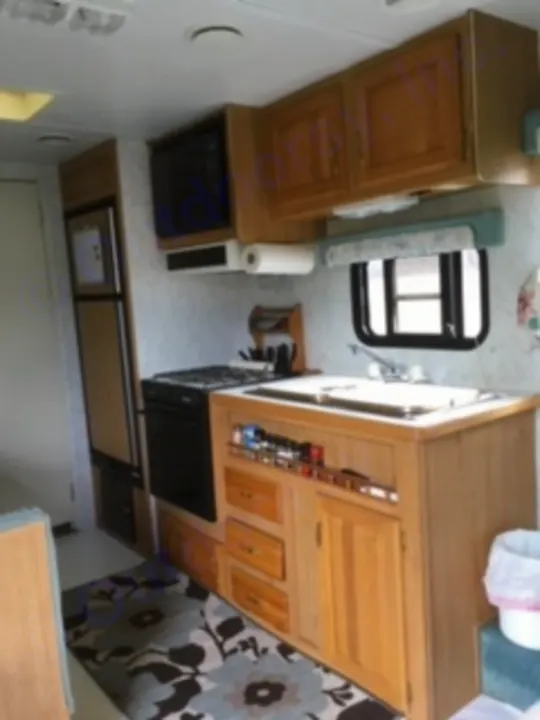 Overhead view of a compact RV rental kitchen and living space. Features include a sink, microwave, fridge, and ample storage.. Electra Electra 1996