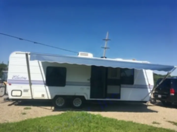 This white "Electra" travel trailer, ideal for an RV rental, is parked with its blue awning extended, offering outdoor shade.. Electra Electra 1996