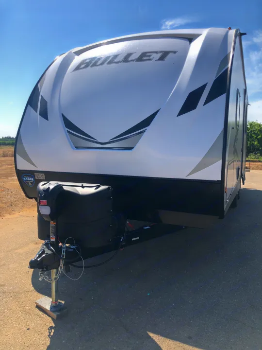 Front view of a white Bullet travel trailer RV rental, parked under a clear blue sky.. Keystone Bullet 2021