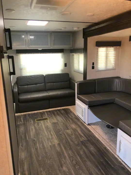 Spacious & modern RV rental interior featuring a comfy sofa, dinette, and wood-look flooring. Perfect for your next adventure!. Keystone Bullet 2021