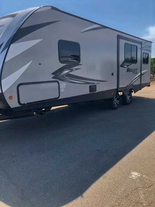Grey and white RV rental: A modern 'Bullet Ultra Lite' travel trailer, ideal for adventure, parked on asphalt.. Keystone Bullet 2021