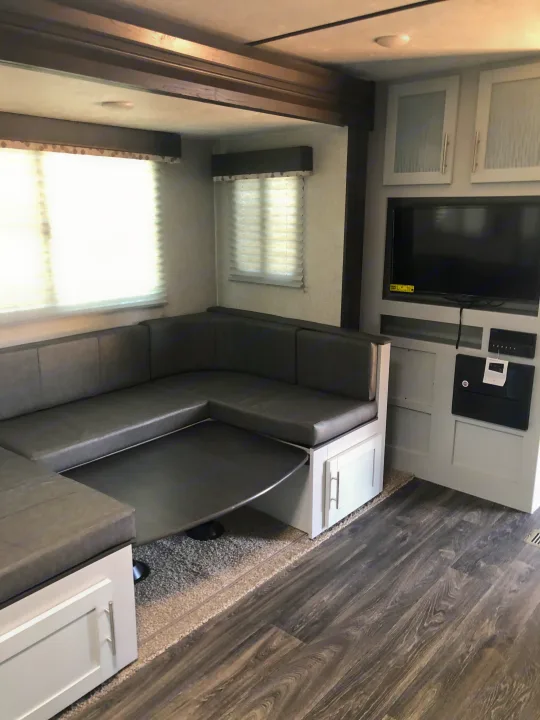 RV rental: Modern interior featuring a U-shaped dinette, lowered table, TV, light cabinets & dark wood floors.. Keystone Bullet 2021