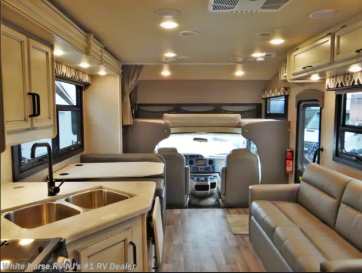 Spacious modern RV rental interior featuring a full kitchen, dinette, living area with sofa, and overhead bunk.. Jayco Greyhawk 2019