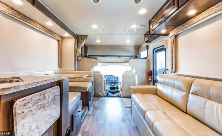 Explore in style with this RV rental! View of modern interior: kitchen, dinette, sofa, driver's cab, and bunk.. Jayco Greyhawk 2019