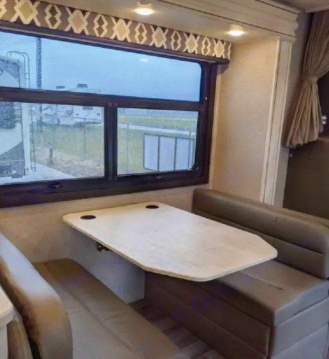 Inside an RV rental: a compact dinette with comfortable benches and a table, offering a view through a large window.. Jayco Greyhawk 2019