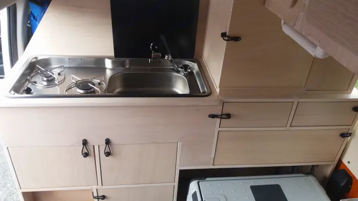 RV rental: Bright wood camper kitchen with two-burner stove, sink, and cabinets. A portable fridge is below.. Toyota Hiace 2006