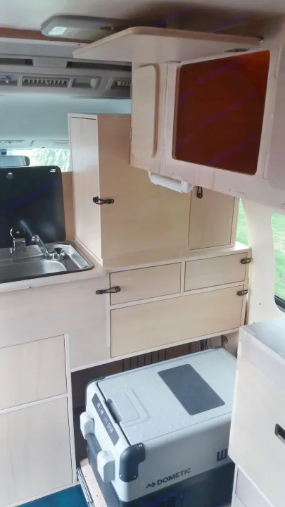 RV rental camper van interior. Light wood cabinets, sink, and pull-out Dometic cooler offer functional storage.. Toyota Hiace 2006