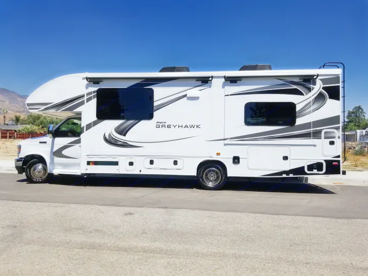 Jayco Greyhawk motorhome RV rental, white with black/grey graphics, parked on asphalt under a clear blue sky.. Jayco Greyhawk 2021