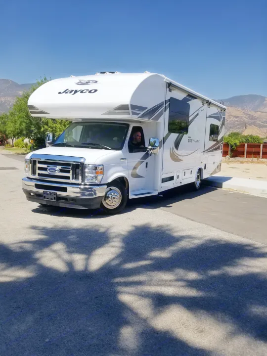 A white Jayco Greyhawk motorhome, ready for RV rental, parked on asphalt with mountains visible in the background.. Jayco Greyhawk 2021