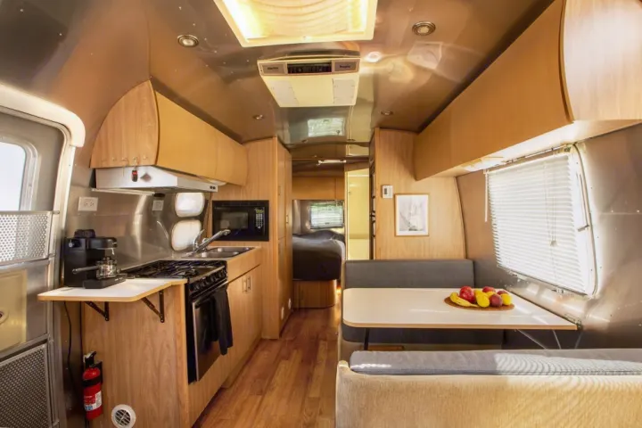 Spacious Airstream RV rental interior with a modern kitchen, comfortable dining area, and cozy bedroom. Ideal travel trailer.. Airstream Safari 2006