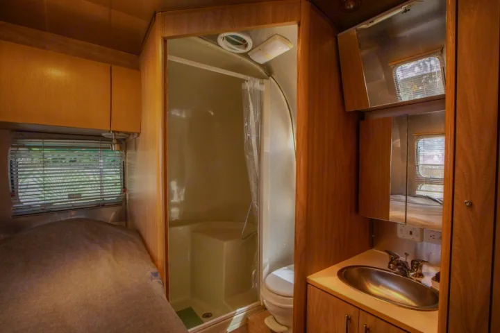Explore this cozy RV rental with a comfortable bed, compact shower, toilet, and sink. Your road trip home awaits!. Airstream Safari 2006
