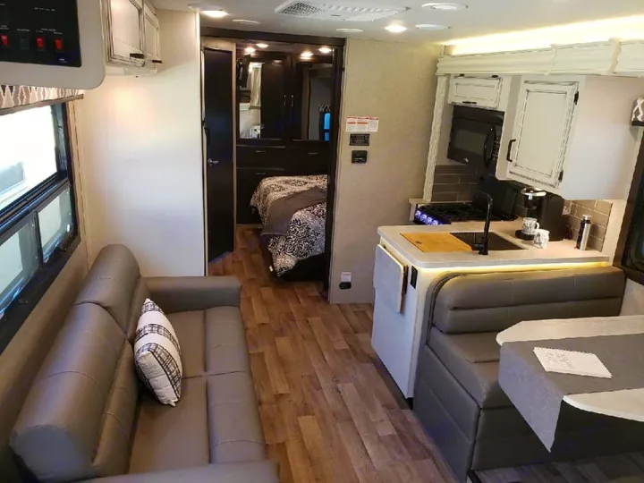Spacious RV rental interior with living room, kitchen, dining booth, and bedroom areas. Modern design.. Jayco Greyhawk 2021