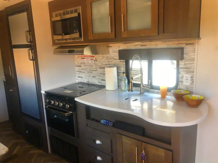 Inside an RV rental kitchen: stove, microwave, sink, fridge, and ample counter space for your journey.. Forest River Evo 2019