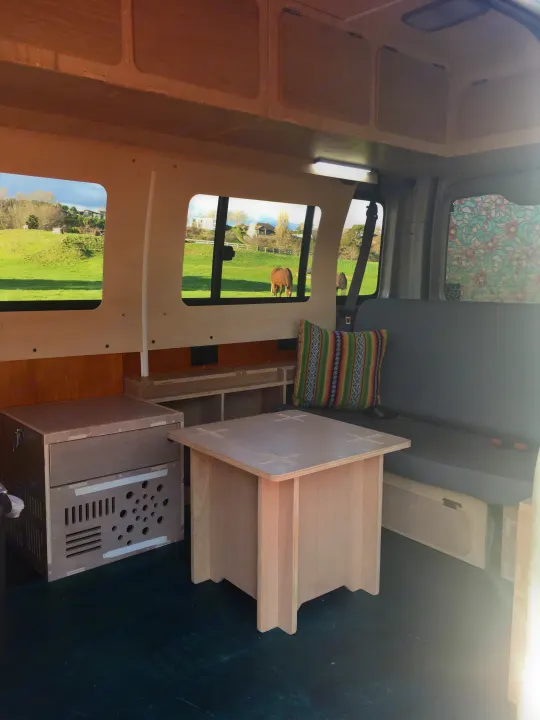 Cozy RV rental interior with custom wood build-out, featuring a scenic window view of horses in a green field.. Toyota Hiace 2006
