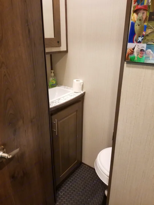 Compact RV rental bathroom with sink, vanity, toilet, and textured floor. Includes soap, toilet paper, and a framed photo.. Other Other 2019