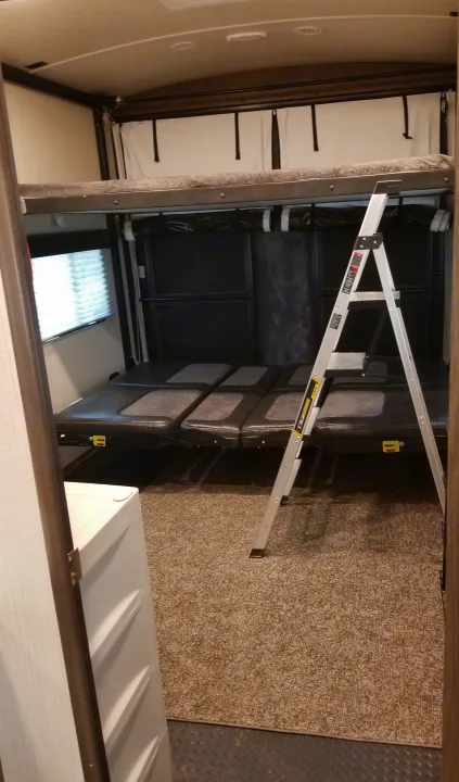Inside an RV rental: a multi-purpose garage with overhead bunk, convertible lower beds, and a stepladder.. Other Other 2019