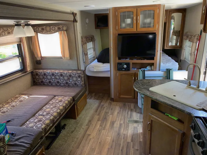 RV rental interior: living area with convertible sofa-bed, compact kitchen, and private bedroom with bed.. Keystone Springdale 2017