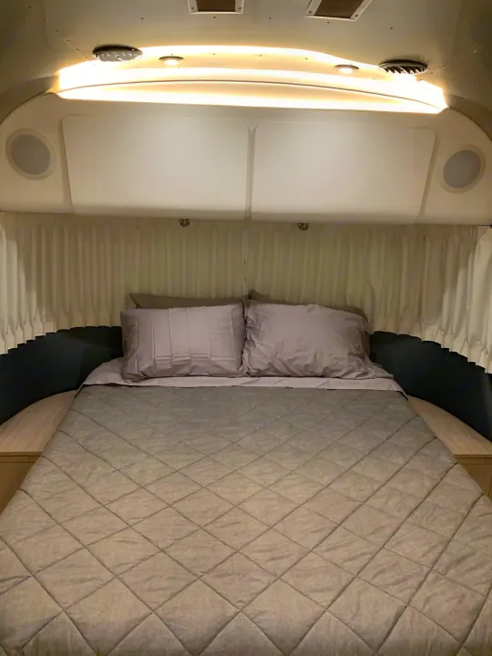 Comfortable RV rental bedroom interior with a modern bed, pillows, and warm lighting, perfect for a cozy night.. Airstream Globetrotter 2019