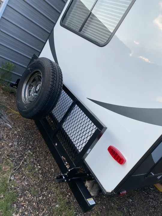 Looking at the back of an RV rental, featuring a spare tire, cargo rack, and a cat lounging underneath.. Forest River Other 2020