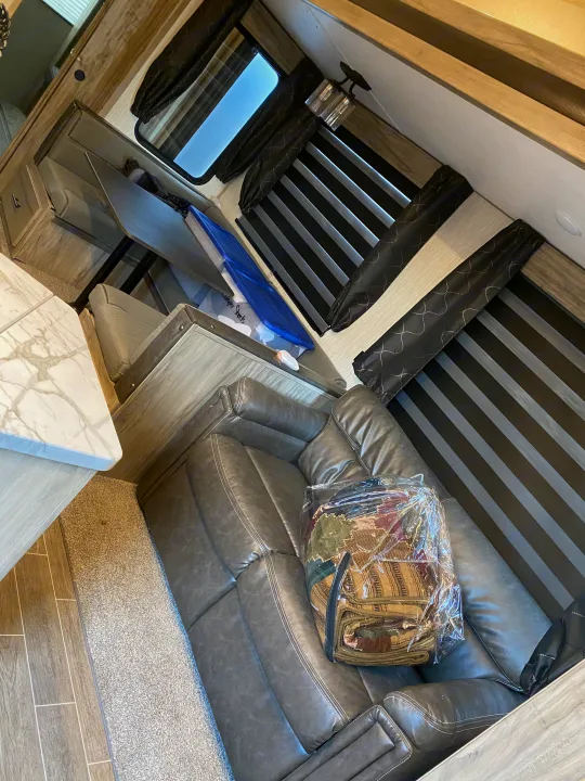 Modern RV rental living space featuring a gray leather sofa, dinette, and stylish window blinds.. Forest River Other 2020