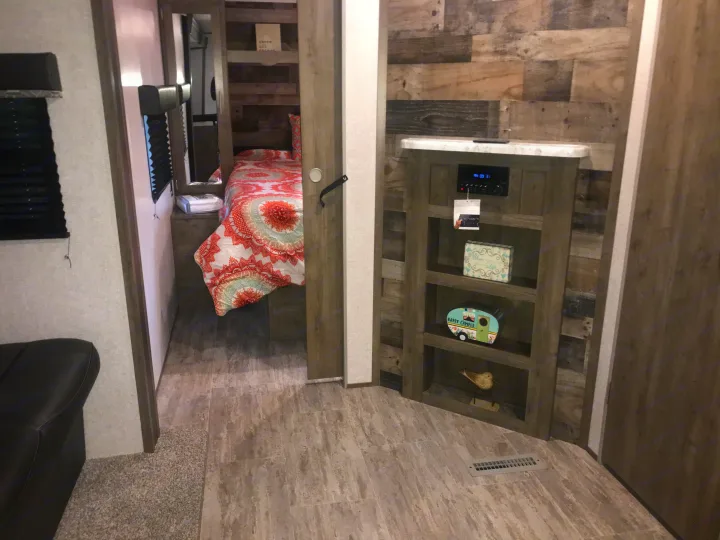 Cozy RV rental interior with a compact bedroom, living area, and entertainment center featuring rustic decor.. Dutchmen Aspen Trail 2021