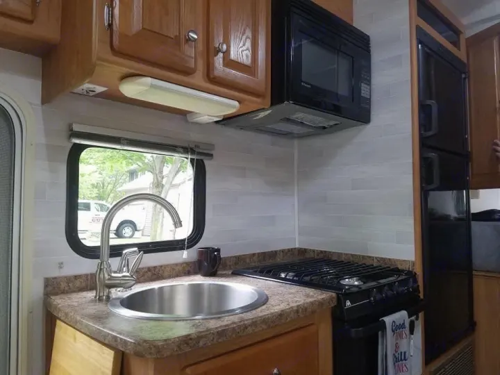 Kitchen area: Large sink, microwave, stove, oven, large refrigerator, and cabinets! Additional counter space pops up on the left side.. Gulf Stream Ultra 2008