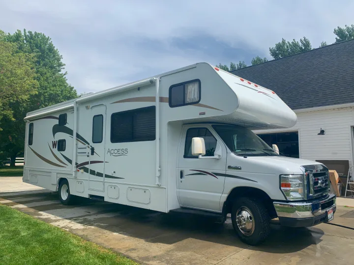 Clean white Class C RV on a driveway, ready for your next RV rental adventure. Perfect for travel & outdoors.. Winnebago Access 2008