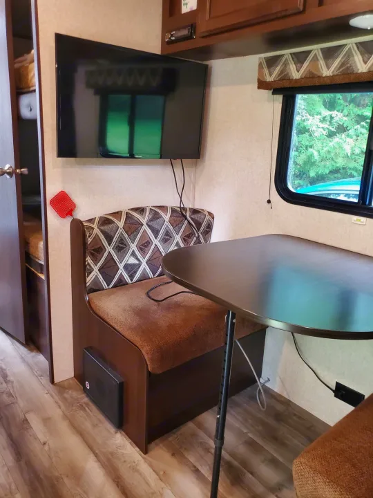 This RV rental features a comfortable dinette booth & wall-mounted TV, creating a functional living space.. Jayco Jay Flight 2018