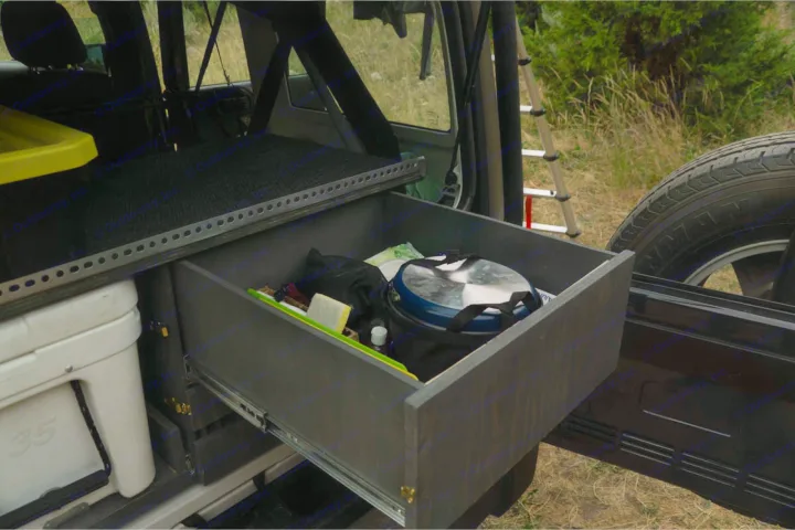 Organized RV rental: A custom pull-out drawer with camping gear, next to a cooler in vehicle storage.. Jeep Wrangler Unlimited 2018