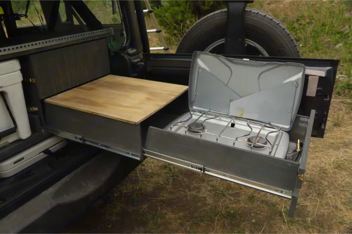 Enhancing your RV rental experience: A vehicle's custom drawer system with a pull-out camp stove and workspace for outdoor cooking.. Jeep Wrangler Unlimited 2018