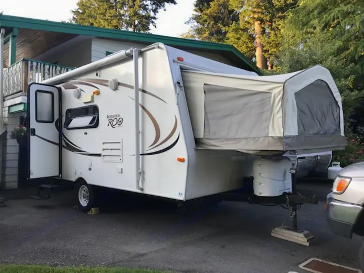 White Rockwood Roo hybrid camper RV rental with pop-out tent extended, parked on asphalt.. Rockwood Roo 2011