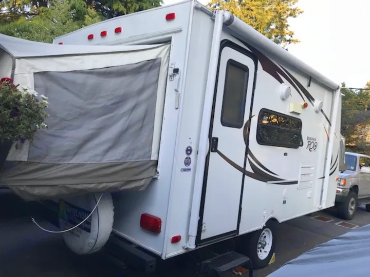 Spacious Rockwood Roo hybrid rv rental travel trailer, with its rear pop-out bed and side awning visible.. Rockwood Roo 2011