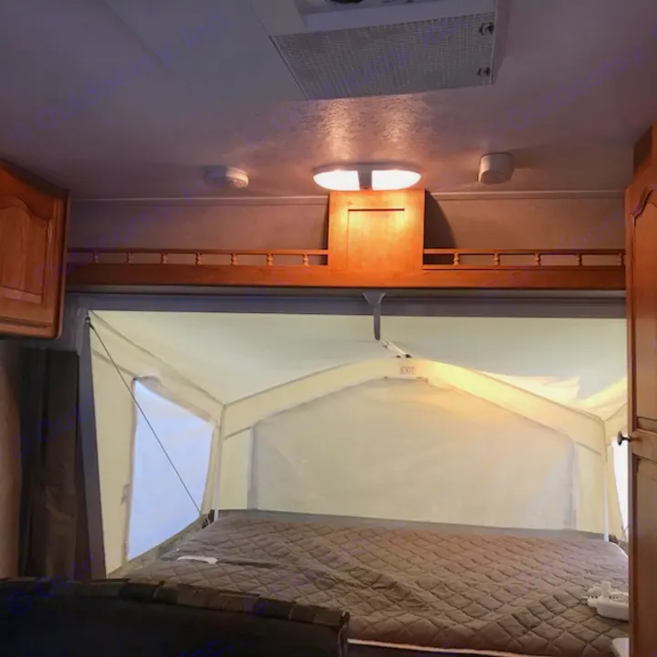 Cozy RV rental interior with an expanded pop-up bed, offering comfy camping.. Rockwood Roo 2011