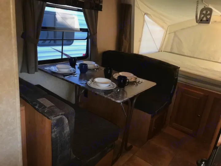 Cozy RV rental interior showing a dinette with place settings and an extendable pop-up bed area, perfect for camping.. Rockwood Roo 2011