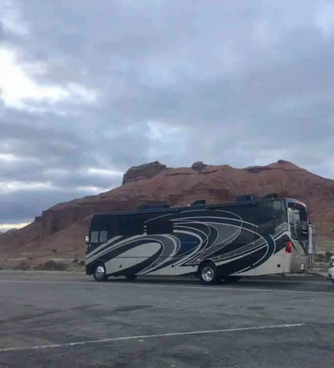 Spacious Class A RV rental parked in a beautiful, rocky desert landscape under a cloudy sky, ideal for travel.. Thor Motor Coach Challenger 2018