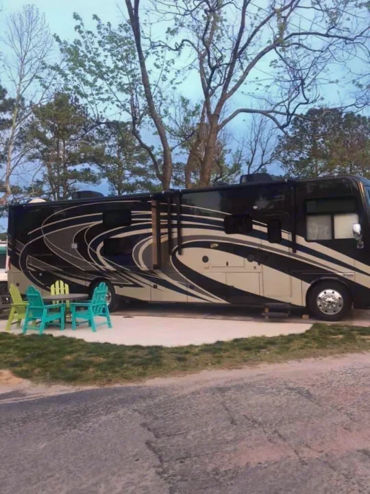Luxury black & white RV rental set up at a pleasant campsite with outdoor furniture.. Thor Motor Coach Challenger 2018