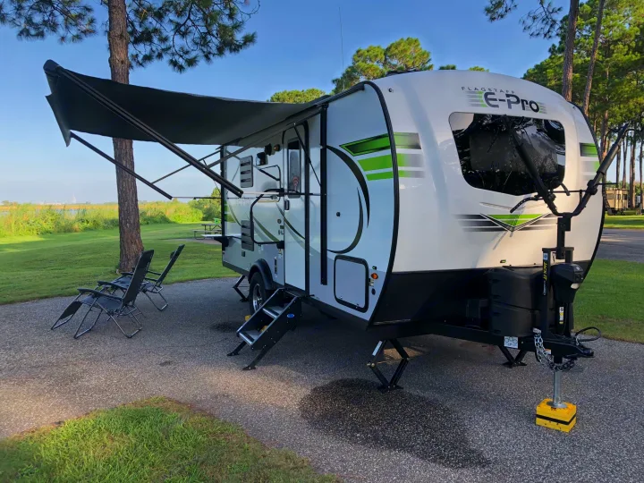 Flagstaff E-Pro travel trailer at a serene campsite with awning extended. Perfect for an RV rental outdoor adventure.. Flagstaff E-pro19BH 2021
