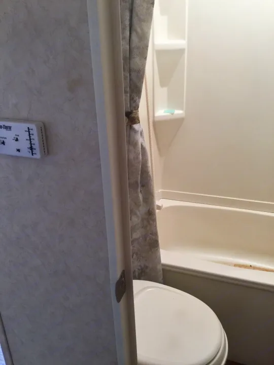 Inside an RV rental: a compact bathroom with a shower-tub, toilet, and a wall-mounted Duo-Therm thermostat.. Max Lite ML26RK 2006