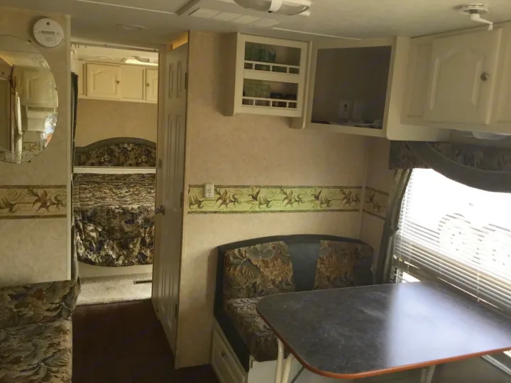 Interior of an RV rental showcasing a comfortable bedroom, dinette, and ample overhead storage.. Max Lite ML26RK 2006