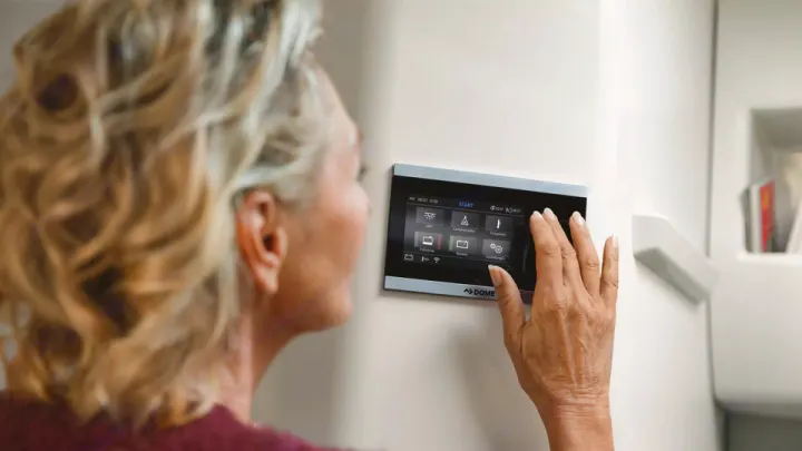 A person's hand interacts with a Dometic smart control panel, managing features like temperature in a modern RV rental.. Volkswagen Grand California 600 2020