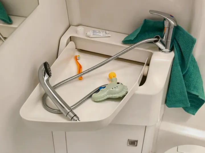 Compact RV rental bathroom: versatile sink, pull-out shower, toothbrush, toothpaste, towel & bath toy.. Volkswagen Grand California 600 2020