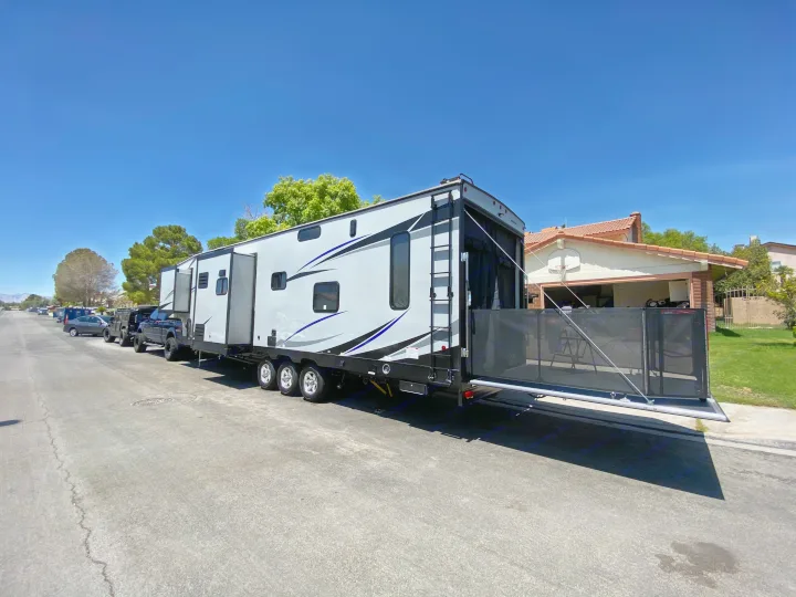 Spacious toy hauler RV rental parked on a sunny residential street with its rear patio deployed.. Forest River Xlr Thunrderbolt 2020