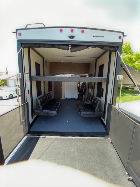 An RV rental toy hauler interior, showcasing a convertible living space with a bunk bed, sofas, and rear ramp.. Forest River Xlr Thunrderbolt 2020