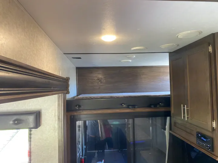 Inside an RV rental: view of a high loft bed, ceiling with lights/vents, wood cabinets, and an audio system.. Forest River Xlr Thunrderbolt 2020
