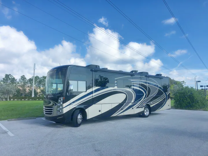 A sleek black, grey, and white Challenger motorhome parked in a lot. Ideal for an rv rental adventure.. Thor Motor Coach Challenger 2018