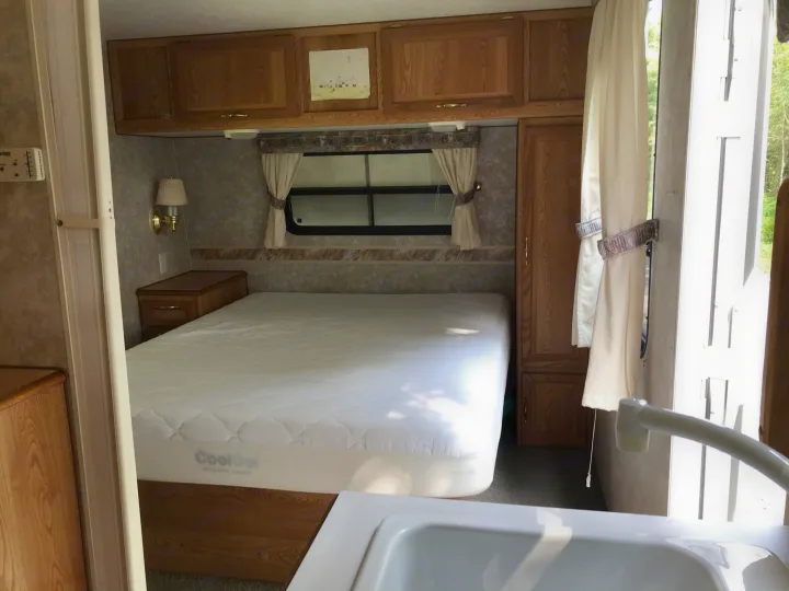 RV rental bedroom view: large mattress, wood cabinets, and window with curtains. Ideal for mobile living and travel.. Sunline Solaris/Delivery&Set-up 2002