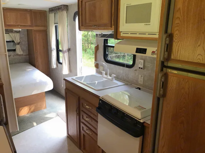 Spacious rv rental interior with a bright kitchen (sink, stove, microwave) and comfortable bedroom area.. Sunline Solaris/Delivery&Set-up 2002